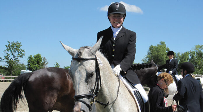 A horse owner riding her horse at a dressage show