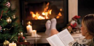 Reading book by the fire and Christmas tree